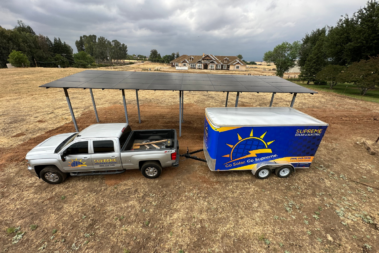 a truck hitched to a supreme solar trailer is parked in front of a solar patio set up on agricultural land