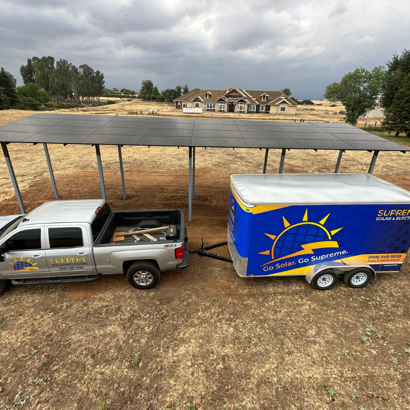 a truck hitched to a supreme solar trailer is parked in front of a solar patio set up on agricultural land