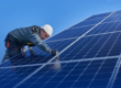 The Latest Solar Panel Technology in 2025 - a solar technician wears a hard hat and checks the solar panels he is working on.