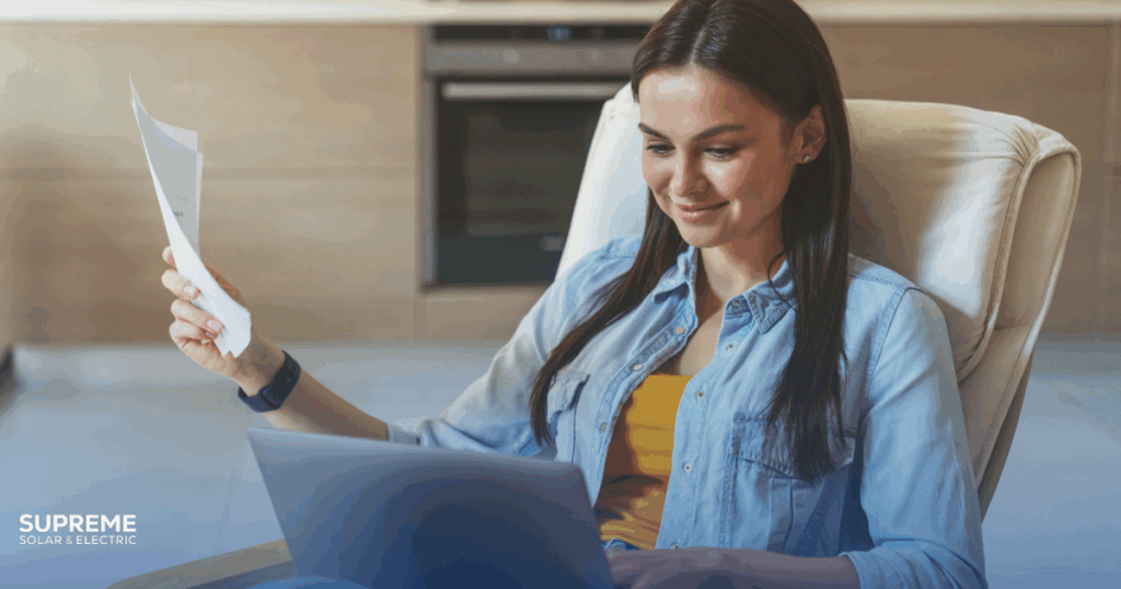 Avoid These 7 Common Mistakes When Installing Solar Panels in Fresno. A woman smiles as she checks her savings on her energy bill and bank account online.