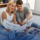 young couple sits on couch and looks over financials